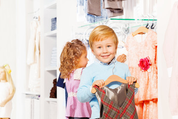 Boy with hanger and girl behind choosing clothes
