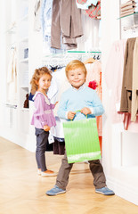 Smiling boy with shopping bag and girl behind