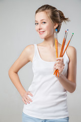 Smiling artist-girl with bunch of paintbrushes.