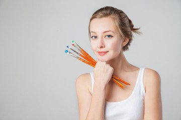 Close-up of smiling artist-girl with paintbrushes.