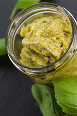 Glass jar with basil pesto on a black plate