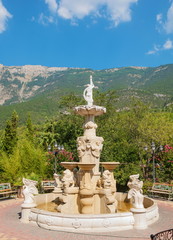 Old fountain in the park on a background of mountains