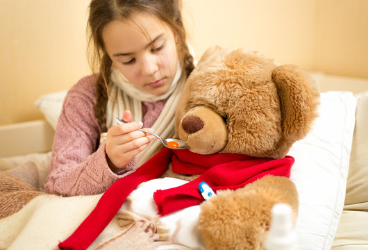 little girl giving medicines to teddy bear