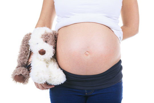 A pregnant woman caressing her belly over white background