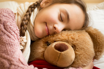portrait of little girl sleeping on brown teddy bear