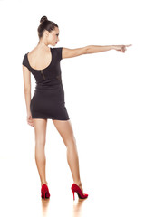 Back view of pretty young woman in short black dress, pointing