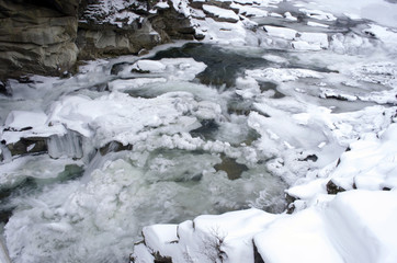 Ice covers rocks in a slow motion river in the winter