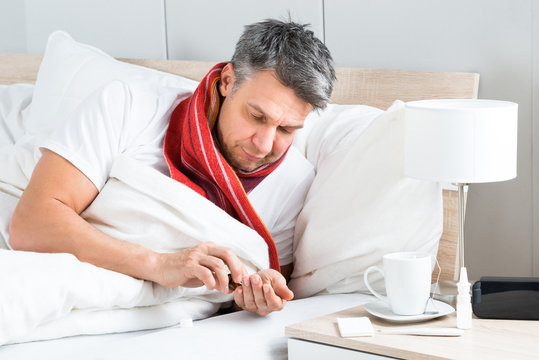 Sick Man Having Medicine In Bed