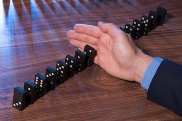 Hand Stopping Dominoes Falling