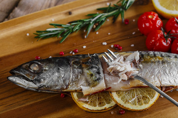 Baked mackerel with tomato and lemon on wooden board