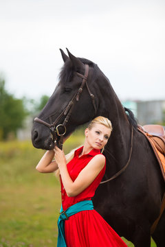 Fashionable blonde woman riding a horse in sunny day. Long hair.