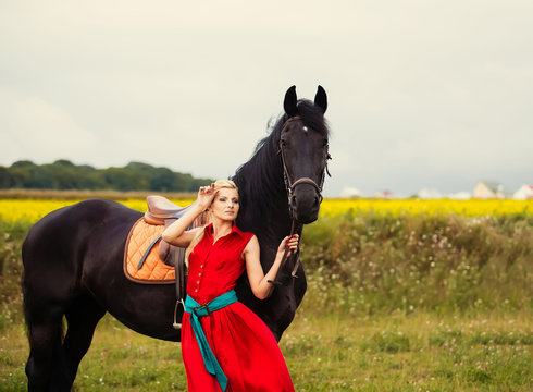 Fashionable blonde woman riding a horse in sunny day. Long hair.
