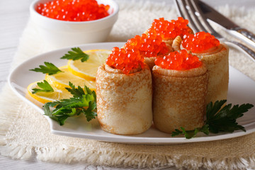 Pancake rolls with red caviar and lemon. Horizontal