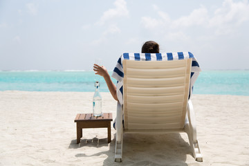 Frau trinkt Wasser am Strand im Urlaub o