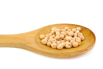 Uncooked chickpeas on wooden spoon on white background.