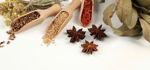 Different spices and herbs in wooden spoons isolated on white
