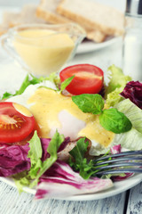 Toast with egg Benedict and tomato on plate on wooden table