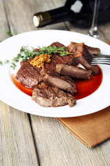 Steak on plate with bottle of wine on wooden background