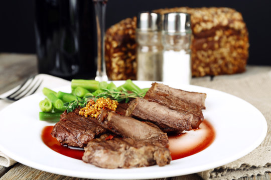 Steak on plate with bottle of wine on dark background