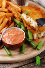 Breaded fried fish fillet and potatoes with asparagus and sauce