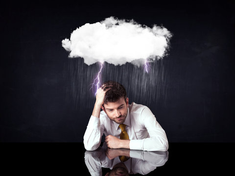 Depressed businessman sitting under a cloud