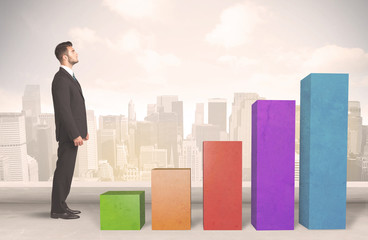 Business person climbing up on colourful chart pillars concept