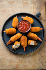 Pan with breaded crab claws and dip sauce, view from above