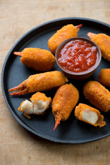 Breaded crab claws and dip sauce on a frying pan, close-up