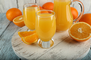 Glass of orange juice with slices on color wooden background