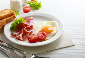 Bacon and eggs on color wooden table background