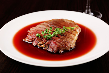 Grilled steak in wine sauce on plate on table close up