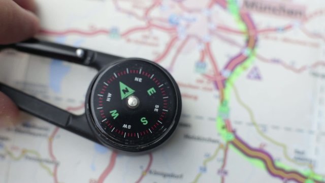Footage of a compas lying over a road map, a person trying to figure out where north is