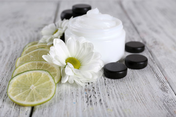 Fototapeta na wymiar Cosmetic cream with slices of lime and spa stones