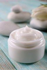 Cosmetic cream with spa stones and tulip on wooden background