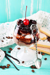Tasty tiramisu dessert in glass, on color wooden background