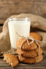 Tasty cookies and glass of milk on rustic wooden background