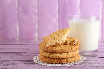Tasty cookies and glass of milk on color wooden background