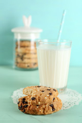 Tasty cookies and glass of milk on color wooden background
