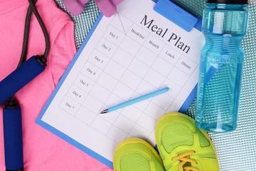 Fototapeta na wymiar Meal plan and sports equipment top view close-up