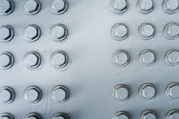 Gray painted metal surface with hexagonal bolt heads