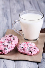 Pink cookies and cup with milk on table close-up