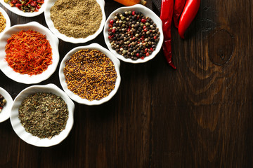 Different kinds of spices in bowls and spoons, close-up,