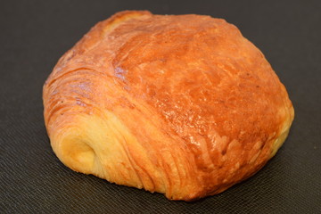 Fresh chocolate croissant on a black background.
