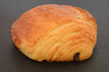 Fresh chocolate croissant on a black background.