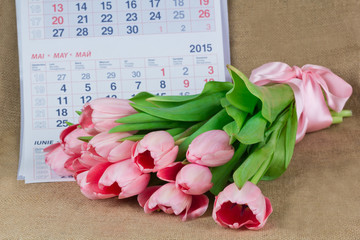 A bouquet of pink tulips lying on the calendar may