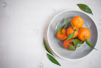 Tangerines with green leaves on white wooden background