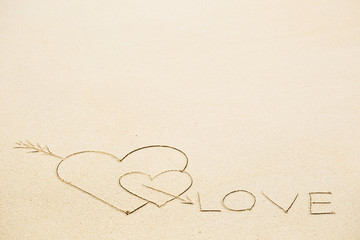 Inscription of Love on wet yellow beach sand