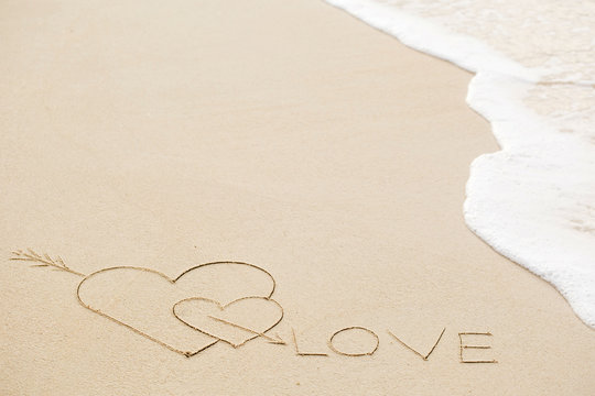 Inscription of Love on wet yellow beach sand