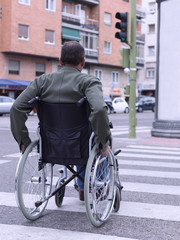 Fototapeta na wymiar Man in wheelchair crossing a zebra