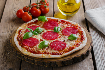 pizza with salami round on a wooden surface